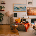 Cozy living room with a bean bag chair, books, and decorative items, showing a framed print of Hokusai's "Surface of lake Misaka, Kai Province" hanging from the wall.