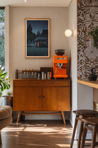Modern kitchen with wooden cabinet, orange espresso machine, and decorative wall art.